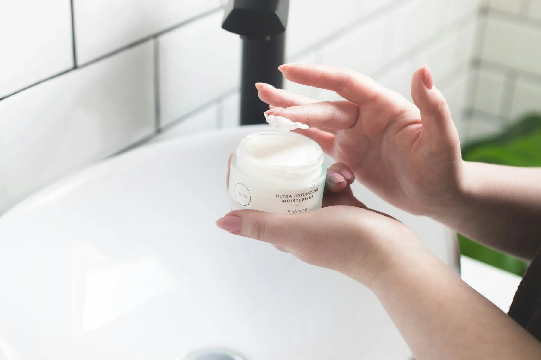 Personne appliquant une crème sur son visage devant un lavabo