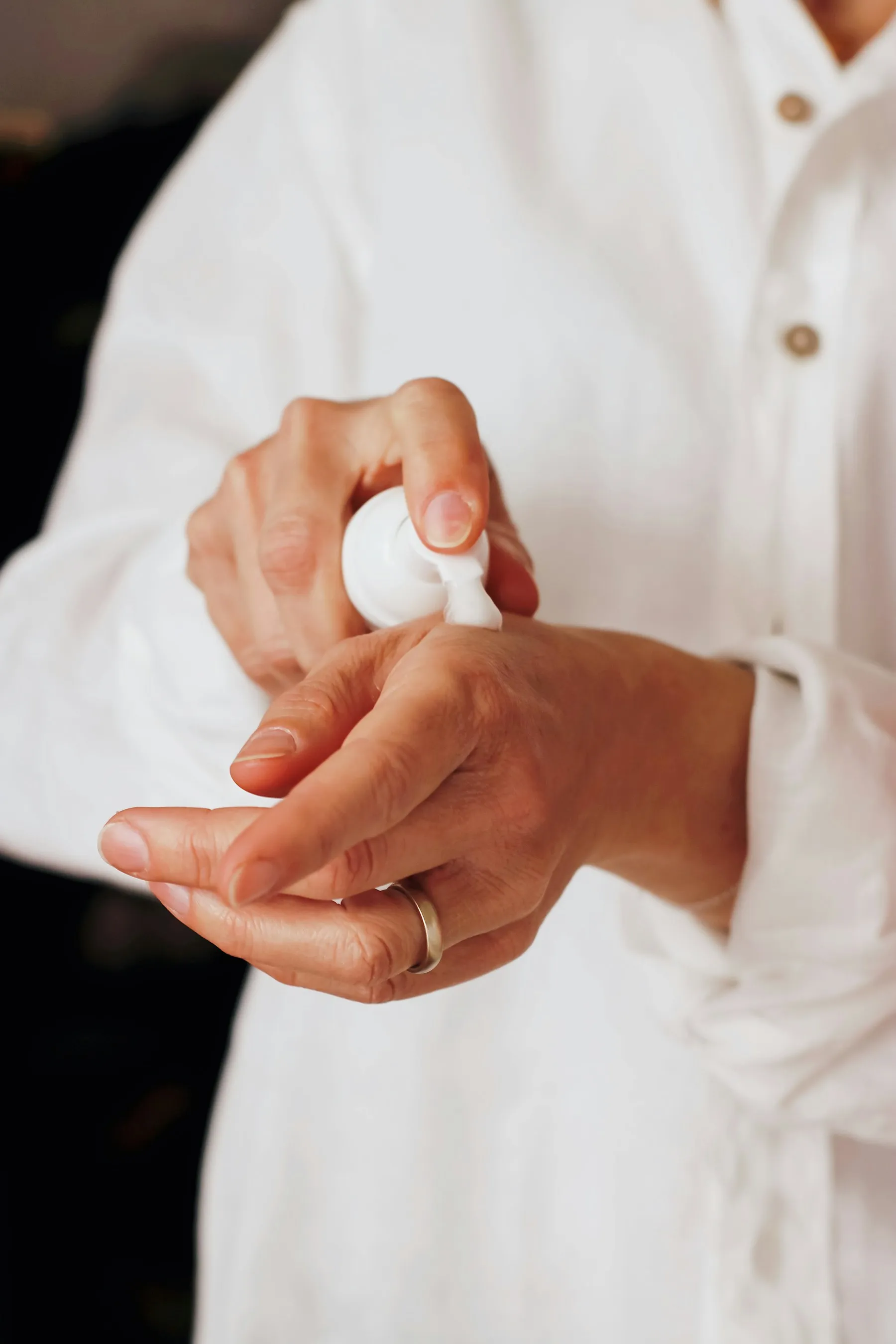 Mains qui font pénétrer une lotion blanche sortie d'un flacon pompe
